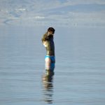 Dead Sea mud covering a person standing on the shore in Israel