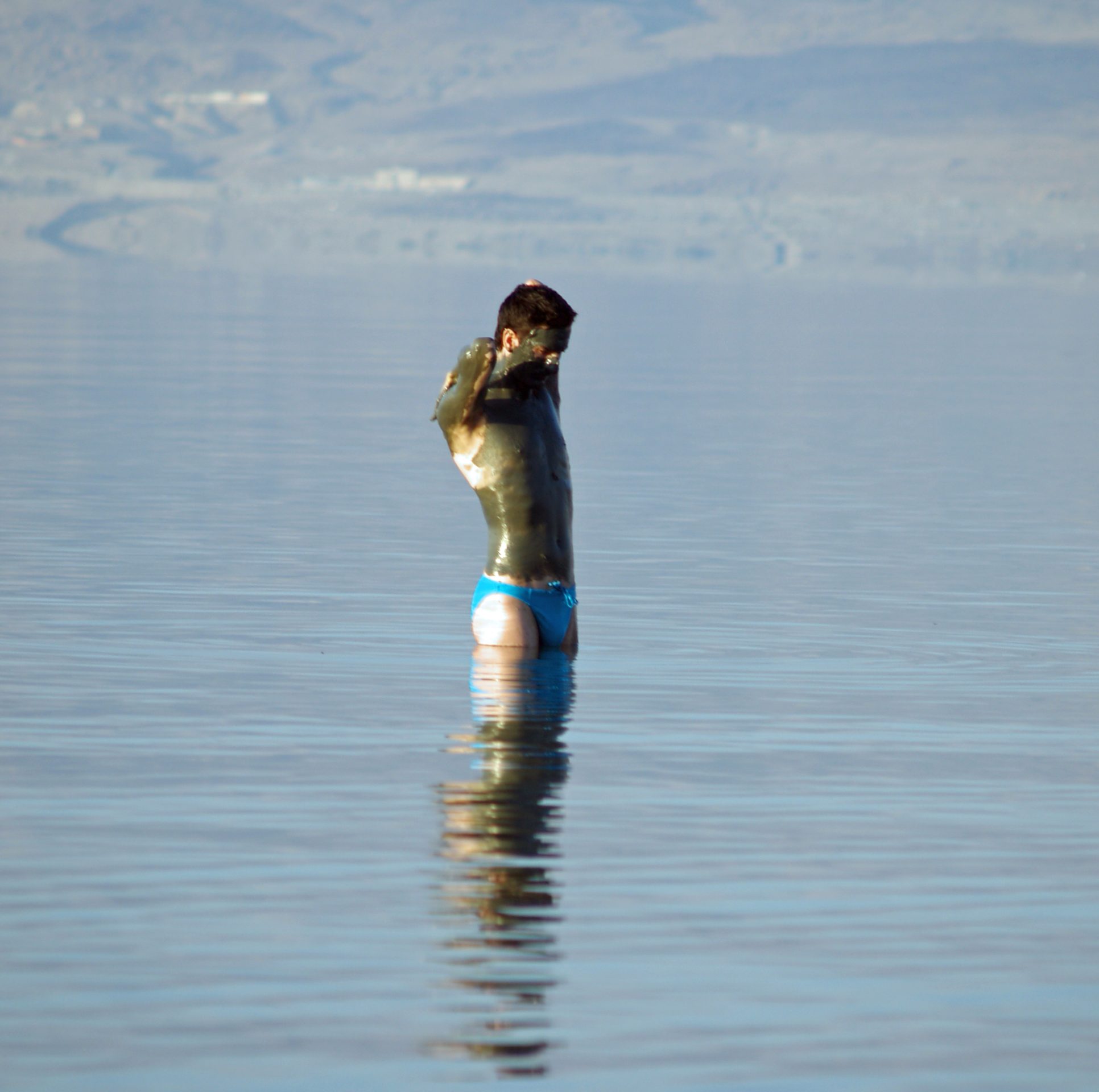 Dead Sea mud covering a person standing on the shore in Israel