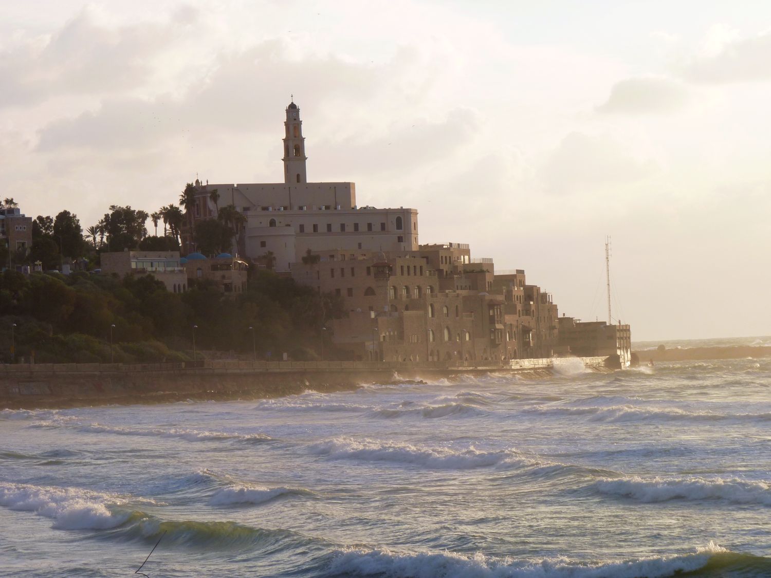 The Old City of Jaffa in Israel seen across the water, honey-colored stone above the Mediterranean with the Tel Aviv skyline beyond