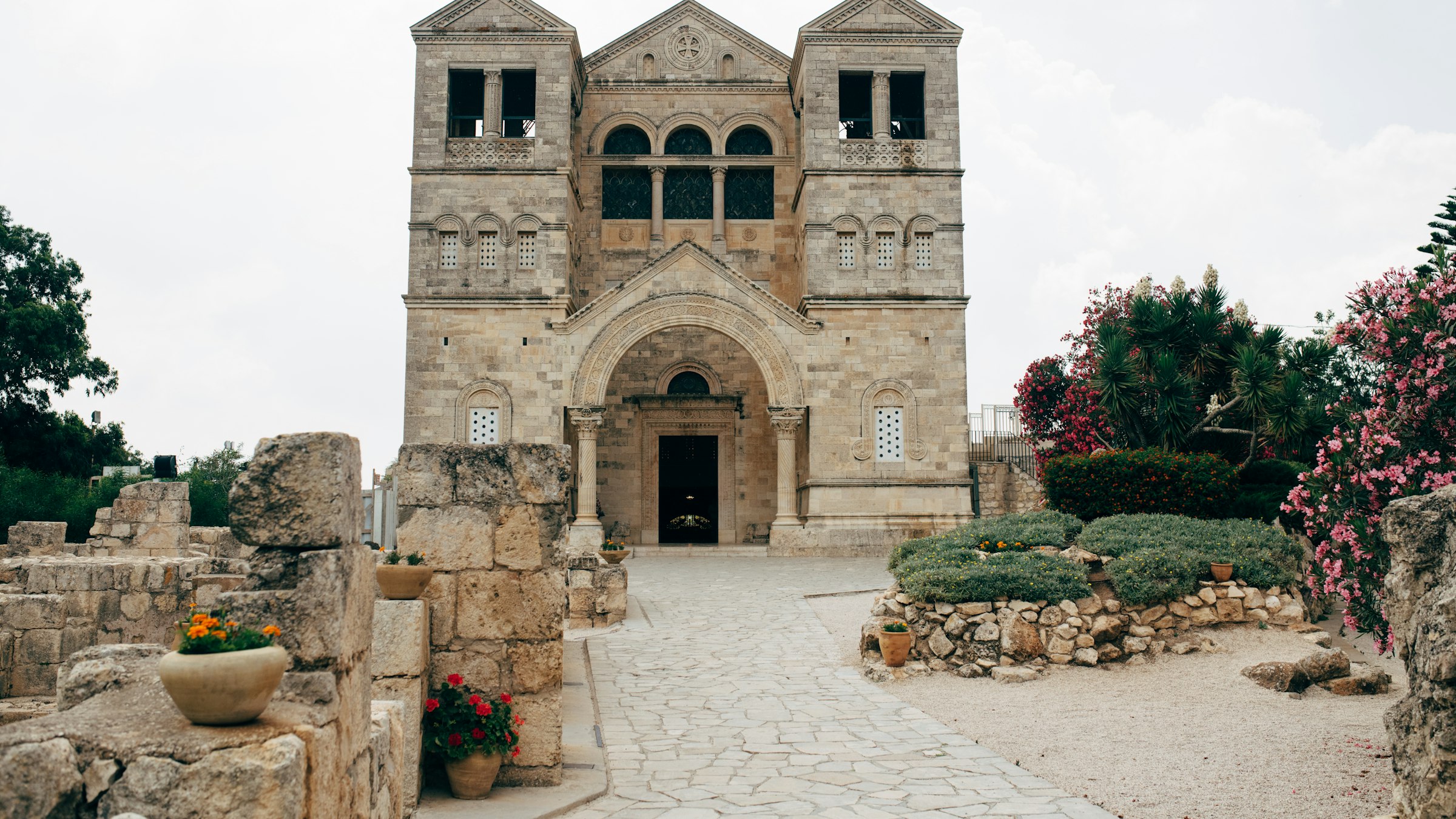 A stone pathway leading toward an ancient building with Mount Tabor rising behind it in the Galilee