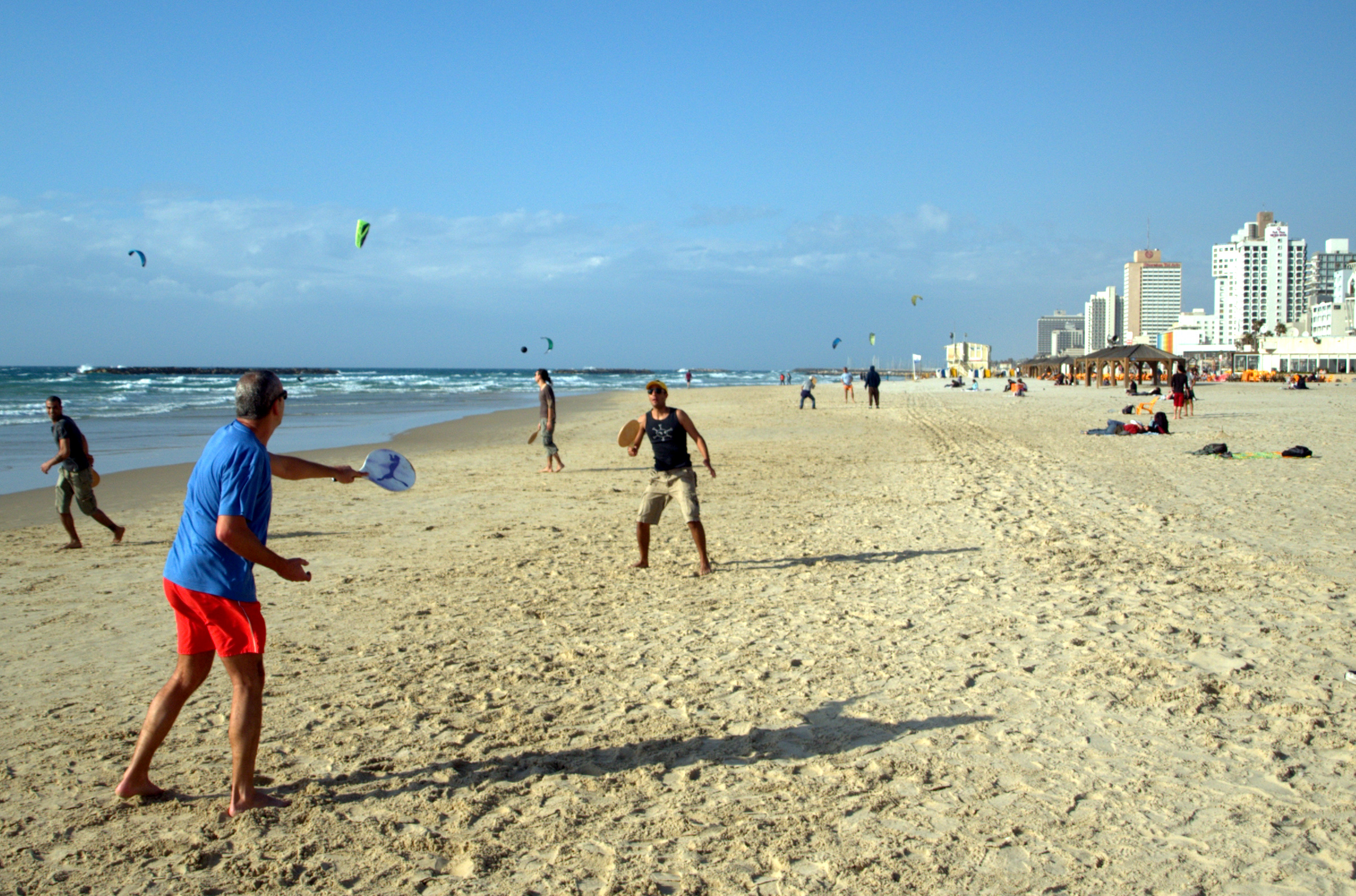 People playing matkot paddleball on a Tel Aviv beach