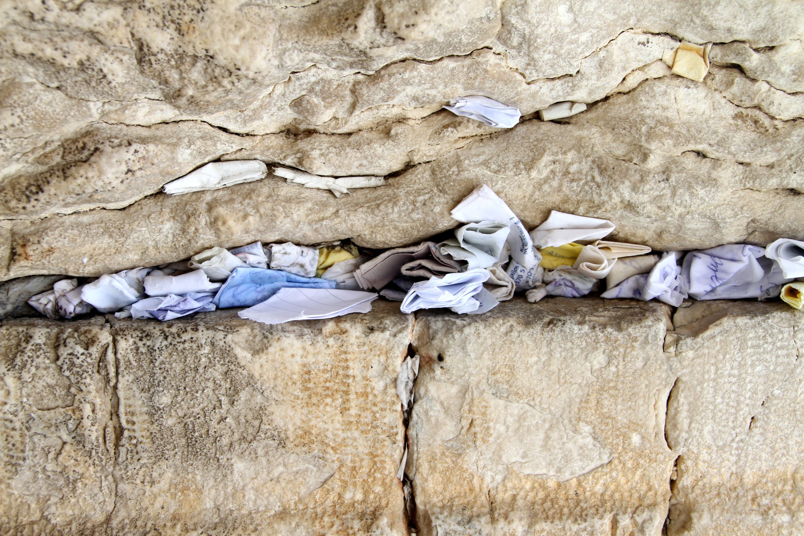 Folded prayer notes tucked into the cracks between the ancient stones of the Western Wall in Jerusalem